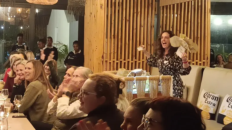 A prize held up to the room, everyone laughing, July 2024