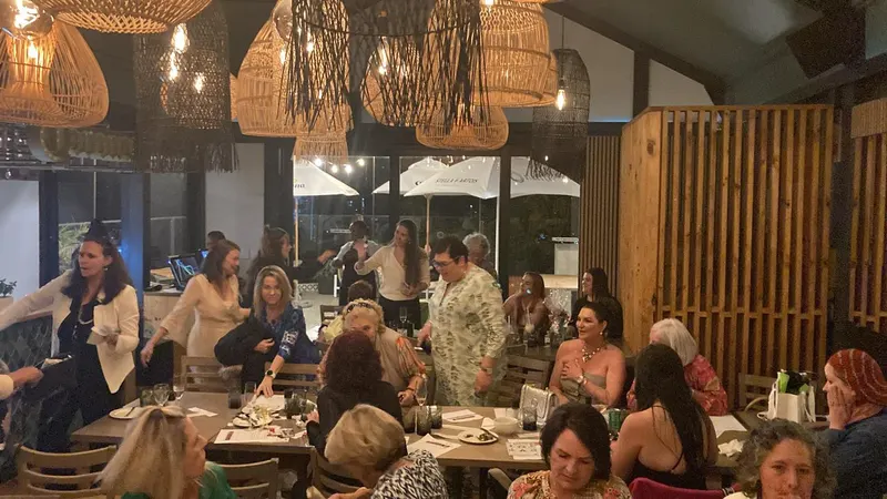 Women talking over dinner at a long table, November 2024